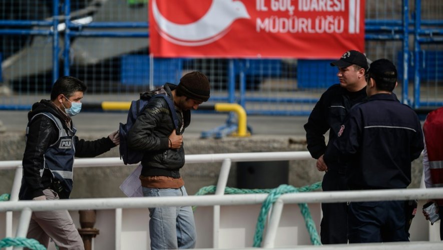 Un policier escorte un des migrants renvoyés par ferry depuis la Grèce jusqu'au port turc de Dikili, le 8 avril 2016