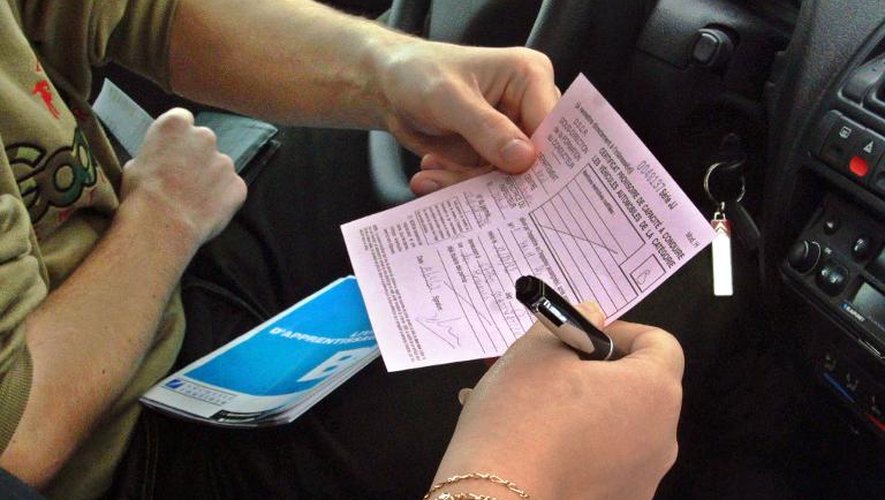 Une inspectrice remet à un élève d'une auto-école un certificat d'aptitude à la conduite après qu'il a passé avec succès l'épreuve de la conduite, à Strasbourg, le 19 avril 2002
