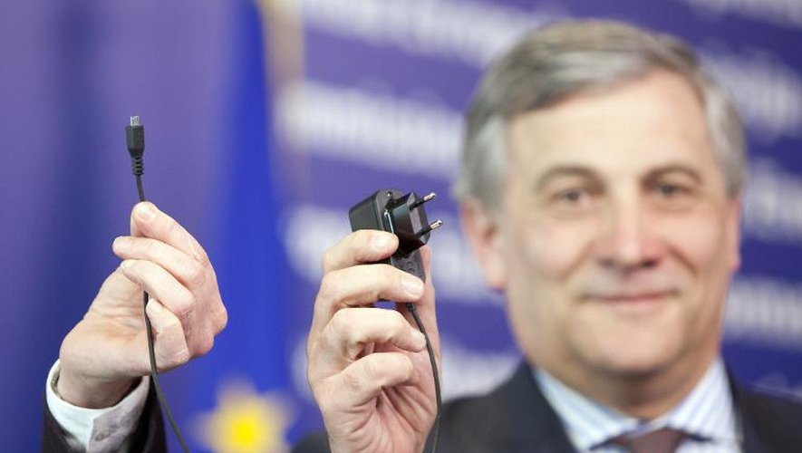 Le commissaire européen Antonio Tajani (D) montre le 13 mars 2014 un prototype d'un nouveau futur éventuel chargeur universel pour téléphone portable, que l'UE s'est engagée jeudi à imposer d'ici trois ans