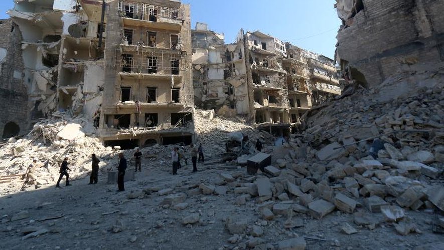 Des Syriens passent entre des immeubles détruits dans le quartier Al-Chaar, dans l'est d'Alep, le 30 mai 2015