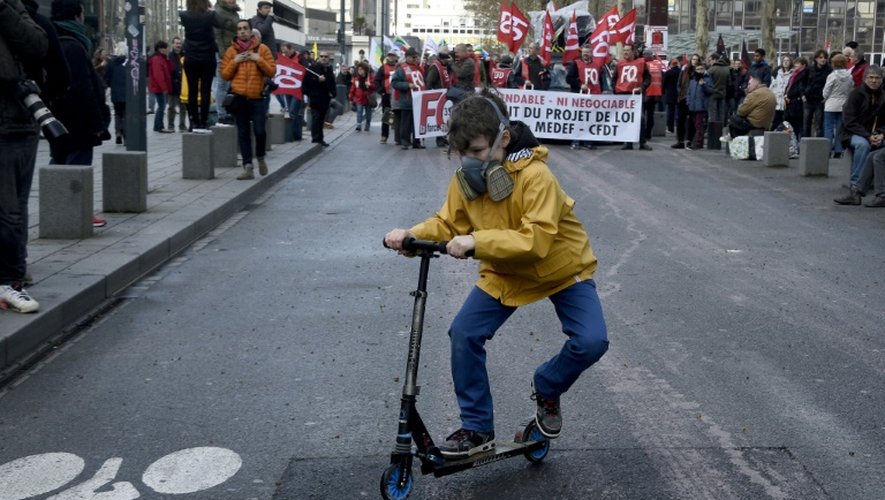 Un enfant portant un masque afin de se protégéer contre d'éventuels tirs de gaz lacrymogènes fait de la trottinette lors de la manifestation contre la loi travail à Rennes le 9 avril 2016