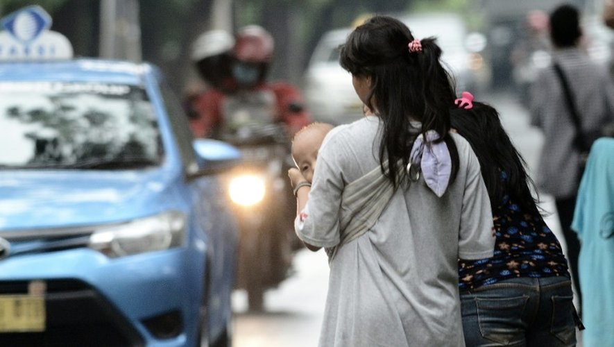 Une femme portant un enfant destiné à faire du co-voiturage à Jakarta, le 31 mars 2016