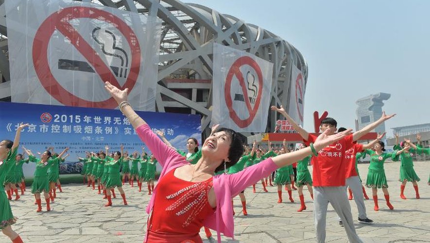 Des femmes et hommes dansent dans le cadre de la campagne du gouvernement chinois pour faire appliquer sa nouvelle loi sur l'interdiction de fumer, le 31 mai 2015 à Pékin