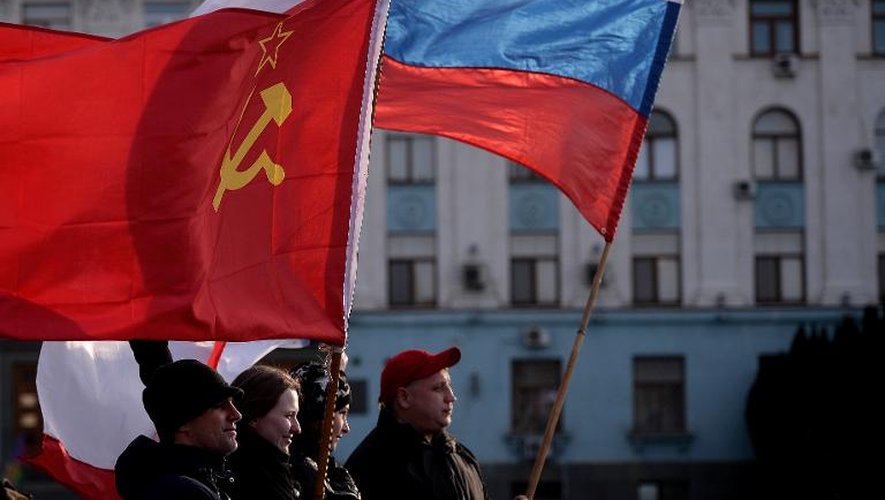 Des hommes agitent des drapeaux soviétique et russe sur la place Lénine à Simféropol, le 16 mars 2014