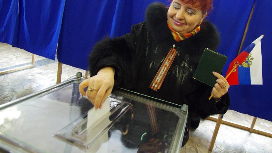 Femme votant avec un drapeau russe à la main dans un bureau de vote de Sébastopol, le 16 mars 2014