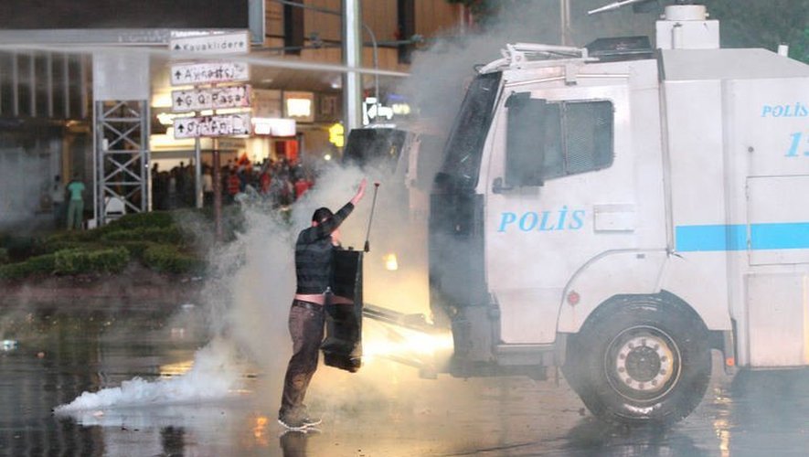 Un manifestant face à un car de police dispersant des gaz lacrymogènes  le 8 juin 2013 à Ankara