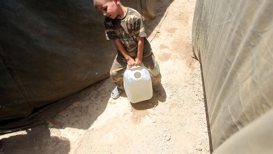 Un petit irakien dont la famille a fui Ramadi, porte un jerrican d'eau dans un camps de réfugiés, le 18 mai 2015 à Bzeibez à la frontière de Bagdad et Anbar