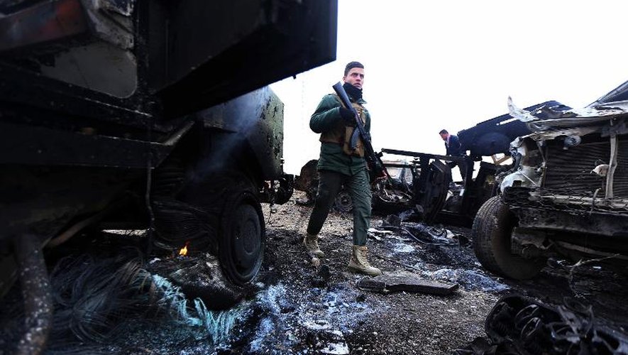 Un combattant Peshmerga au milieu carcasses de voitures après un attentat du groupe Etat islamique à Kesarej en Irak, le 18 décembre 2014