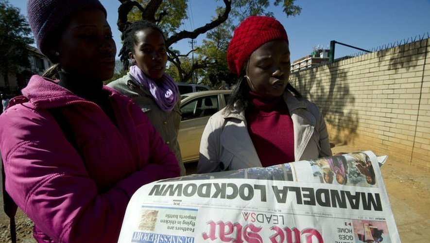 Mandela à la Une d'un quotidien sud-africain que lisent des jeunes femmes le 10 juin 2013 devant l'hôpital spécialisé de Pretoria