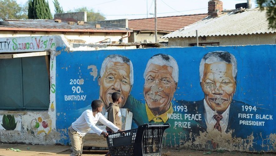 Un enfant passe devant des portraits peints de Nelson Mandela à Soweto, le 29 mars 2013