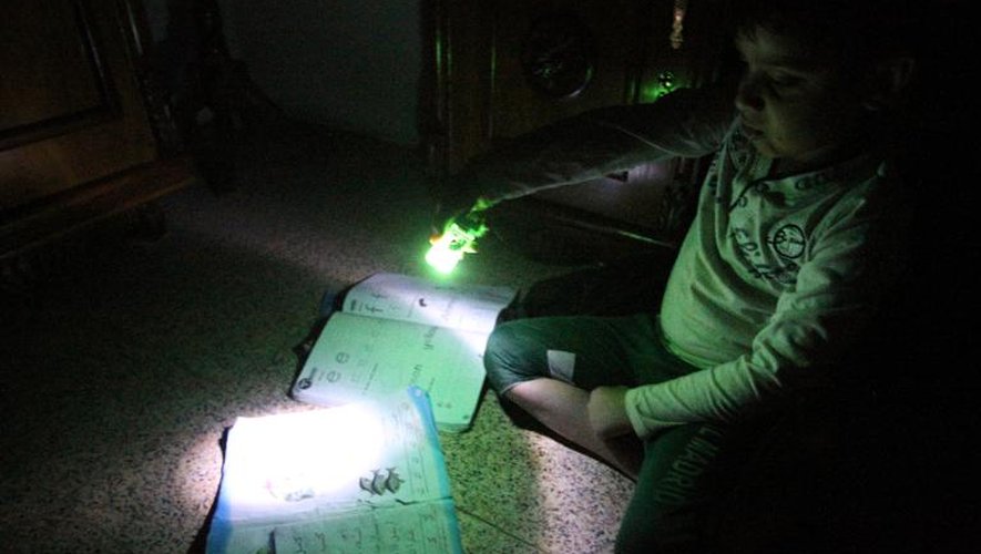 Un petit garçon utilise une lampe électrique pour faire ses devoirs durant une coupure de courant à Bagdad le 19 mars 2014