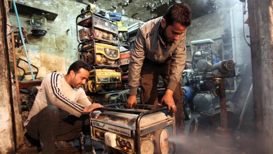 Deux hommes inspectent un générateur électrique utilisé pour faire face aux coupures de courant, le 19 mars 2014 à Bagdad