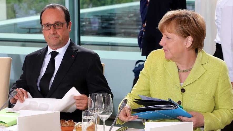 Le président français François Hollande (G) et la chancellière allemande Angela Merkel (D) lors d'un dîner de travail avec le président de la Commission européenne, le 1er juin 2015 à Berlin