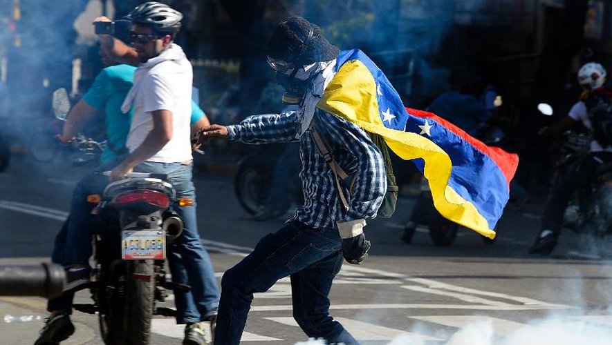 Un opposant au président vénézuélien Nicolas Maduro retourne une grenade lacrymogène lors d'une manifestation à Caracas le 22 mars 2014