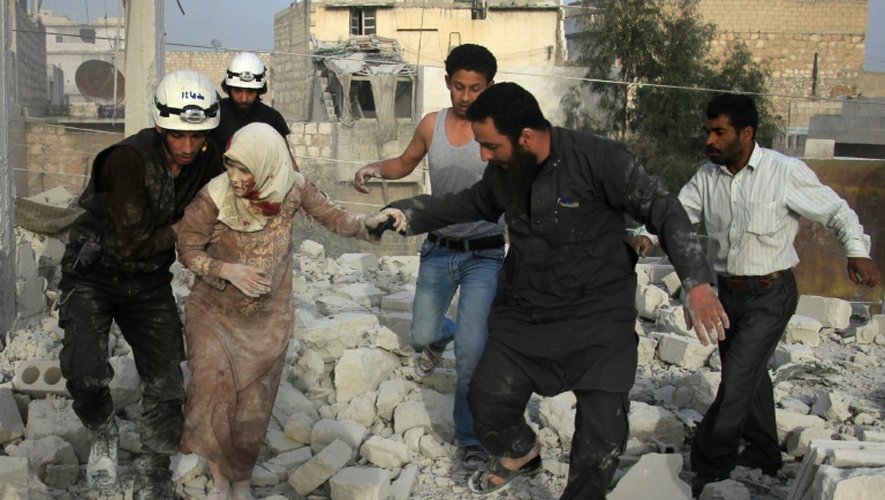 Des secouristes syriens aident une femme blessée à se sortir des décombres, après une frappe aérienne des forces gouvernementales contre le quartier d'Hadariya tenu par les rebelles, le 10 avril 2016 à Alep
