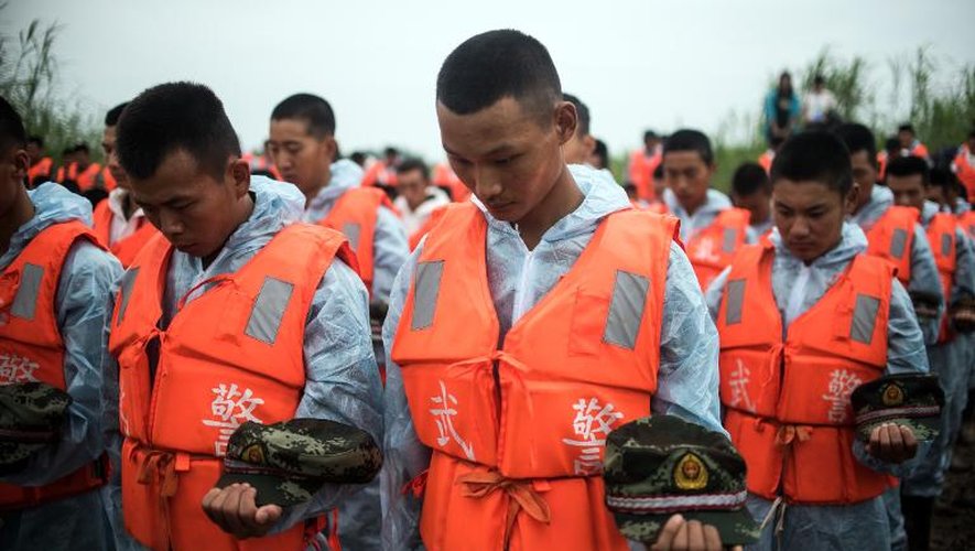 Des secouristes lors de la cérémonie de deuil le 7 juin 2015 sur la berge du Yangtsé, devant l'épave du bateau