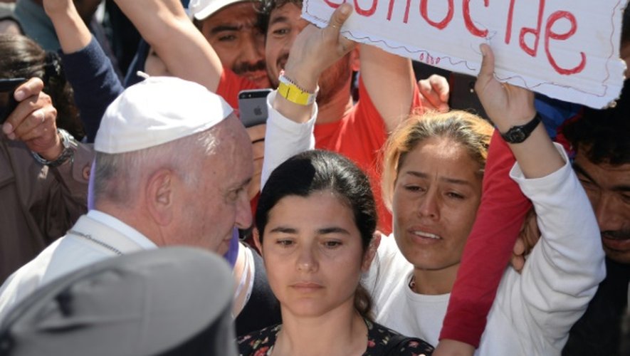 Des femmes brandissent des pancartes appellant à sauver du génocide le peuple Yazidi, lors de la visite du pape François sur l'île de Lesbos, le 16 avril 2016