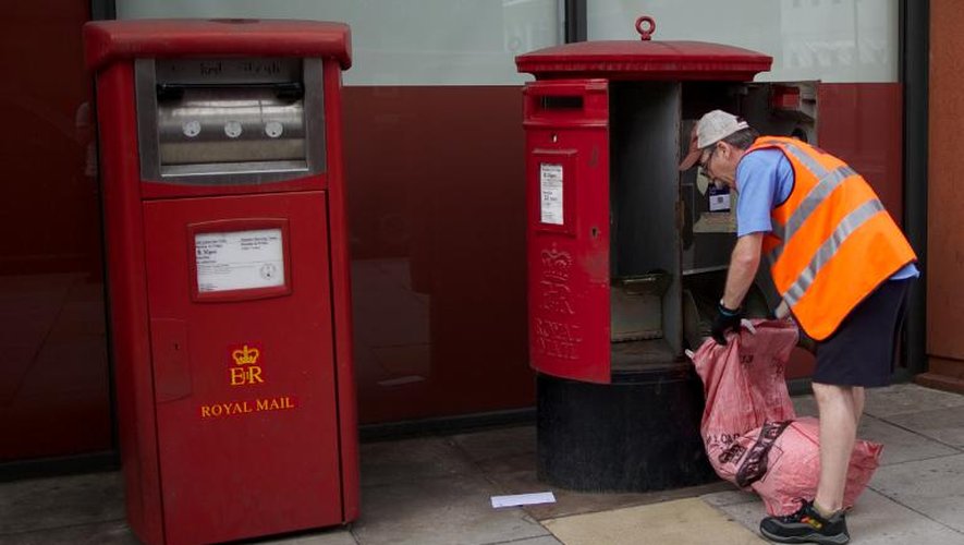 Un postier vide une boîte aux lettres de la Royal Mail à Londres, en juin 2013