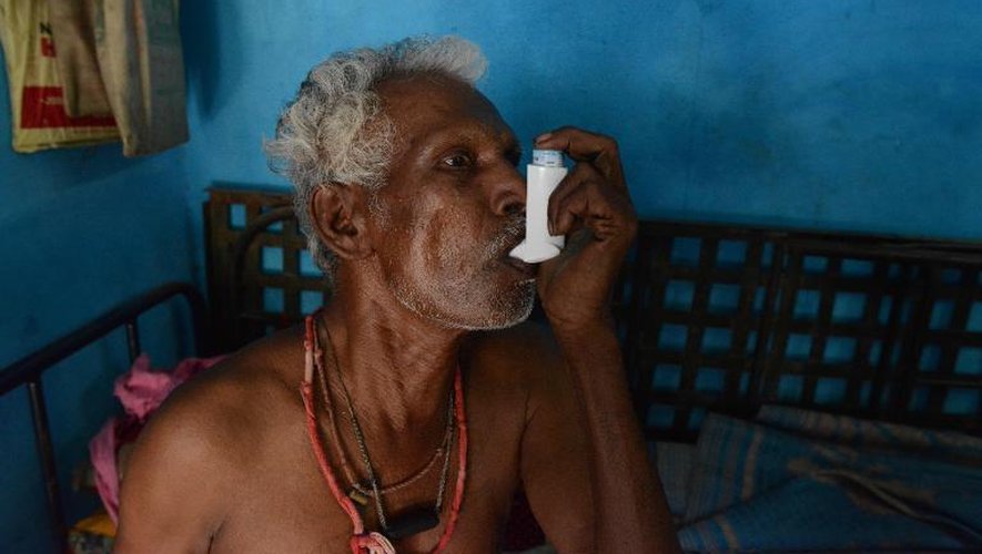 Chinnapan Chinnakannu utilise son inhalateur, le 7 mai 2015 chez lui près de Ahmedabad, pour surmonter ses difficultés respiratoires après des années de travail dans une usine d'amiante ciment en Inde