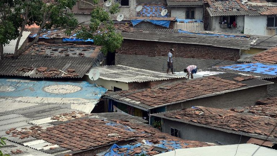 Des Indiens réparent les toits en amiante de leurs maisons dans un bidonville près de Bombay, le 6 juin 2015
