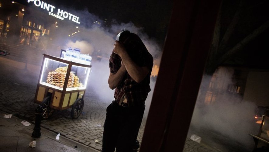 Un vendeur de rue se couvre le visage pour se protéger des gaz lacrymogènes dans le parc Gezi à Istanbul, le 15 juin 2013