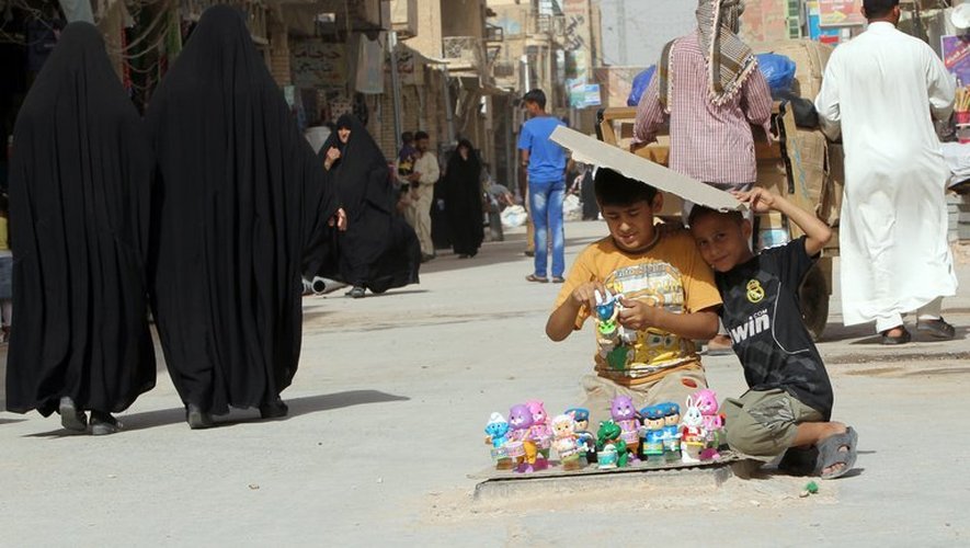 Deux enfants irakiens vendent des jouets sur la route qui mènent au mausolée de l'Imam Ali, à Najaf, en Irak, le 11 juin 2013