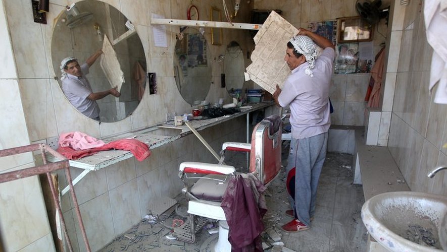 Un homme déblaie son échoppe de barbier après une explosion à Aziziyah, au sud de Bagdad, le 16 juin 2013