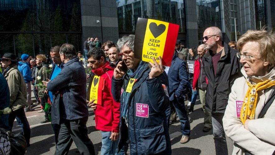 Un homme tient une pancarte aux trois couleurs de la Belgique avec la mention en anglais "restons calme et aimons la Belgique" lors de la marche pacifique contre le terrorisme à Bruxelles le 17 avril 2016