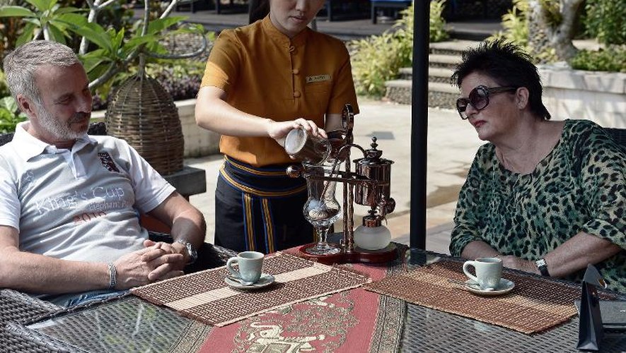 Deux touristes allemands, Gerd et Barbara Schautz, s'apprêtent à déguster un Black Ivory Coffee préparé par une employée du complexe hôtelier Anantara, à Chiang Saen, dans le nord de la Thaïlande, le 10 avril 2015