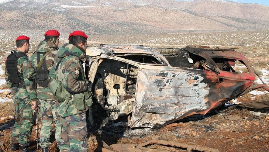 Des soldats libanais se tiennent à côté de la carcasse d'une voiture détruite dans une explosion le 17 décembre 2013 dans la plaine de la Bekaa