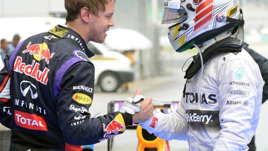 Lewis Hamilton (d), auteur de la pole position du Grand prix de Malaisie de F1, serre la main de Sebastian Vettel, qui sera à côté de luji sur la première ligne de la grille de départ, le 29 mars 2014 sur le circuit de Sepang