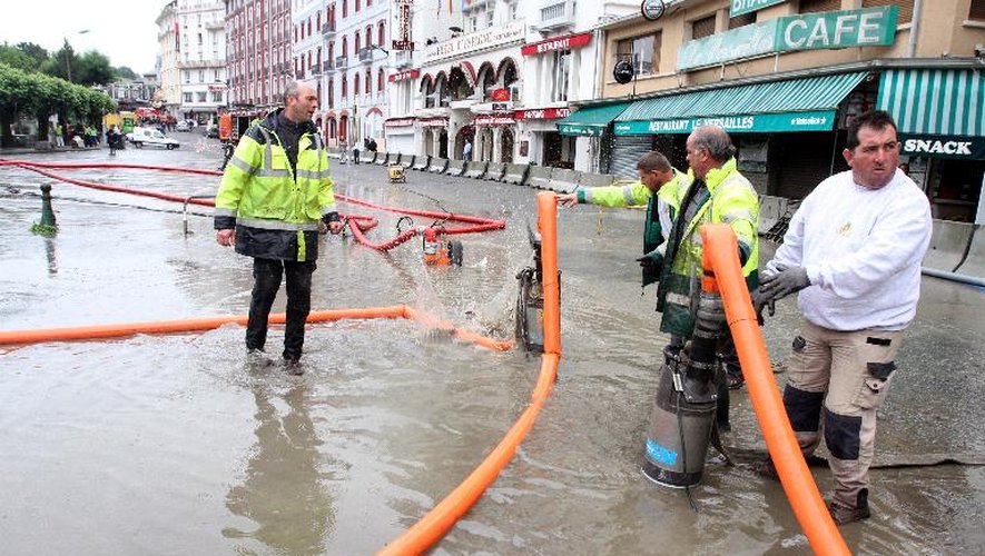 Des employés municipaux s'activent pour pomper l'eau dans une rue inondée de Lourdes, le 18 juin 2013