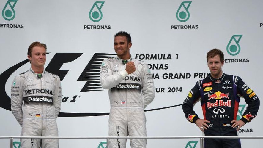Le pilote britannique de l'écurie Mercedes Lewis Hamilton (C) entouré par Nico Rosberg (G) et Sebastian Vettel (D) sur le podium du Grand Prix de Malaisie, le 30 mars 2014 sur le circuit de Sepang