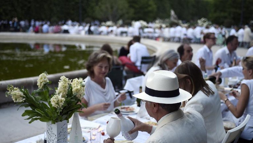 Un homme habillé en blanc sert le 11 juin 2015 un verre de champagne lors de la 27è édition du "dîner en blanc" dans les jardins du Palais Royal à paris