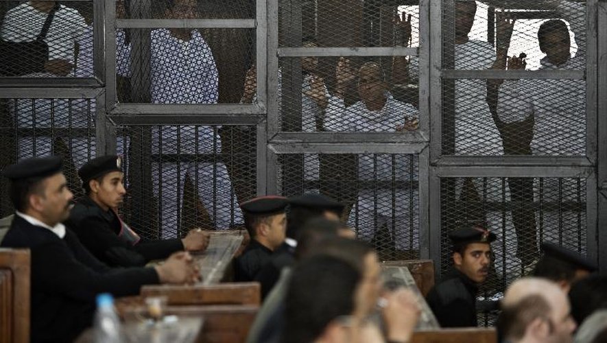 Le journaliste australien Peter Greste (3e d.) d'Al-Jazeera et ses collègues dans le box des accusés lors de leur procès pour soutien présumé aux Frères musulmans dans la prison Tora au Caire, le 5 mars 2014