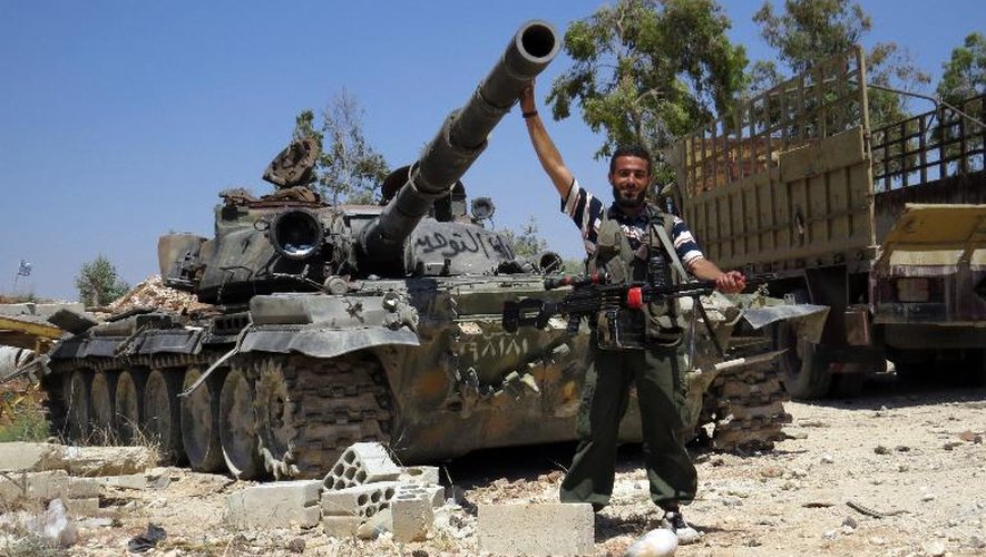 Un rebelle syrien devant un char qui aurait été confisqué à l'armée dans la ville de Sermin, dans le nord-ouest de la Syrie, le 14 juin 2013