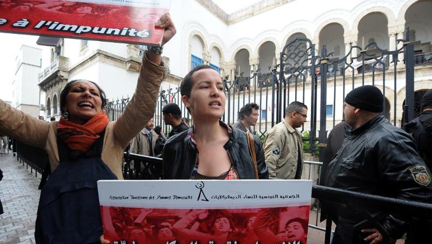 Amina Sboui, féministe tunisienne, qui fut déténue trois mois pour avoir posté des photos d'elle poitrine nue sur internet, brandit une pancarte lors d'une manifestation les violences faites aux femmes, le 31 mars 2014 devant le tribunal de Tu