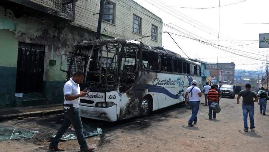 Les enquêteurs inspectent la carcasse d'un autobus incendié par un gang en représailles du non-paiement d'un "impôt de guerre", le 29 avril 2015 à Tegucigalpa, au Honduras