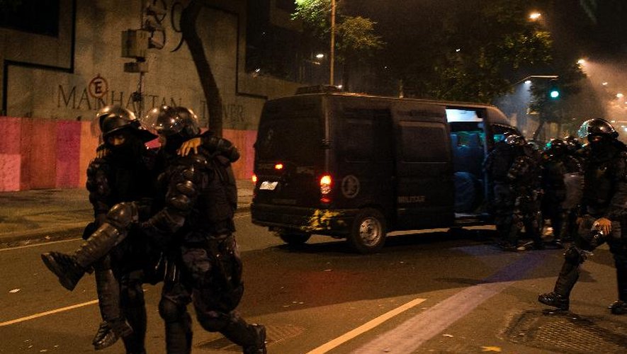 Des policiers portent l'un de leurs collègues blessés lors des violents afrontements, le 20 juin 2013 à Rio