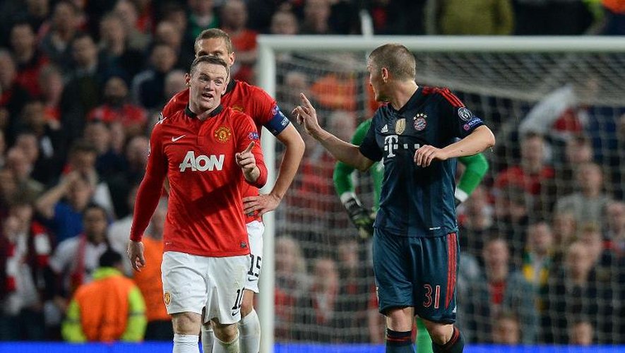L'attaquant de Manchester United Wayne Rooney en discussion avec le milieu de terrain du Bayern Munich Bastian Schweinsteiger (R) pendant le quart de finale aller de la Ligue des champions, l 1er avril 2014 au stade d'Old Trafford à Manchester