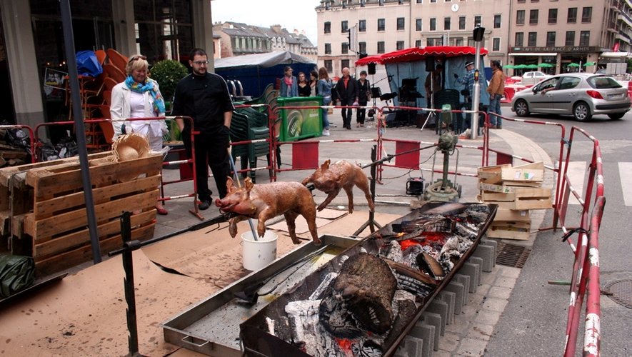 Ambiance fête de village avec les cochons grillés devant un café de la place d'Armes