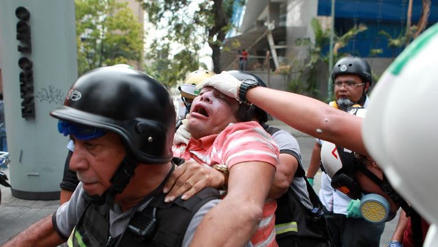 Un pompier aide un manifestant qui proteste contre le gouvernement de Nicolas Maduro à Caracas le 1er avril 2014