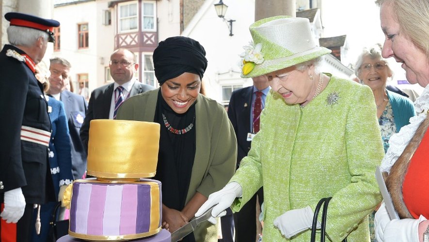 La reine Elizabeth coupe un gateau préparé par Nadiya Hussein (g), gagnante d'un concours de pâtisserie, à Windsor lors d'une sortie le jour de ses 90 ans, le 21 avril 2016