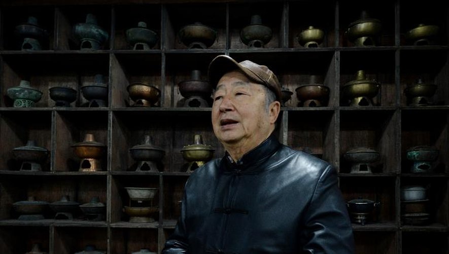 Le "roi de la fondue" Nie Ganru avec quelques trésors de sa collection de marmites à fondue, dans son musée de Chongqing (Chine), le 22 février 2014