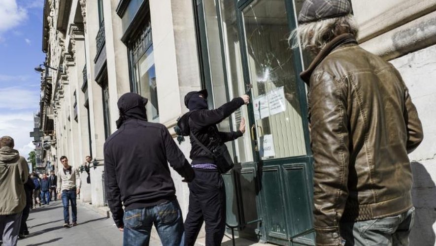 Un homme casse la vitre d'une banque, lors d'une manifestation contre le fascisme et en l'honneur de la mémoire de Clément Méric, le 23 juin 2013 à Paris