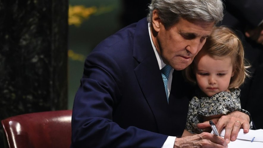 Le secrétaire d'Etat américain  John Kerry signe l'accord sur le climat, tenant sa petite-fille, le 22 avril 2016 à l'ONU à New York