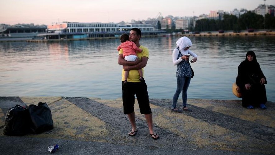 Un migrant porte son enfant dans ses bras après être arrivé au port du Pyrée près d'Athènes, le 14 juin 2015