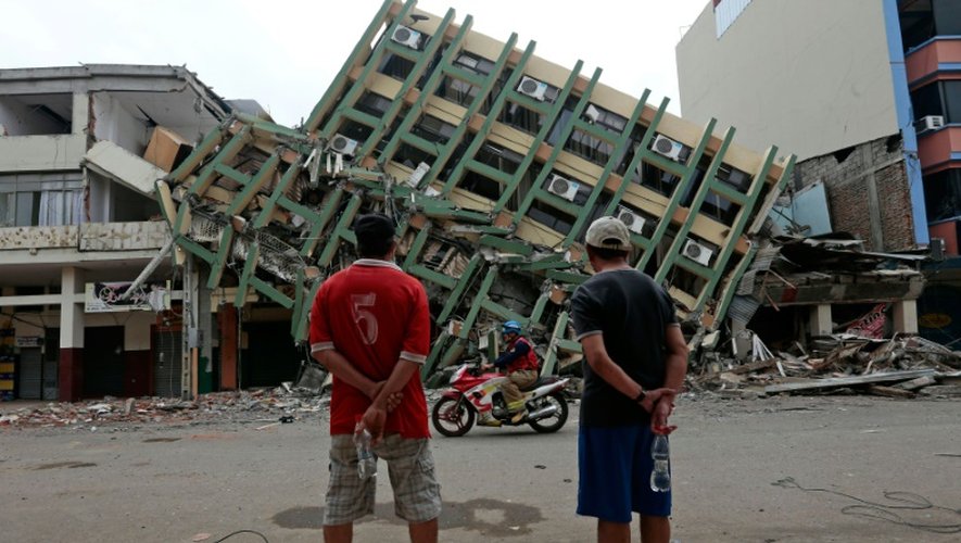 Deux hommes regardent un immeuble détruit à Portoviejo, en Equateur, le 21 avril 2016, une semaine après le violent séisme qui a ravagé le pays