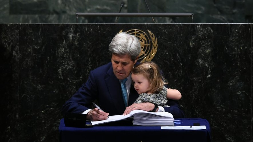 Le secrétaire d'Etat américain John Kerry signe l'accord sur le climat tenant sa petite-fille, à l'ONU à New York, le 22 avril 2016