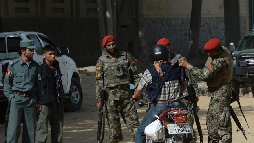 Des hommes chargés de la sécurité fouillent un motocycliste près du palais présidentiel à Kaboul, le 25 juin 2013